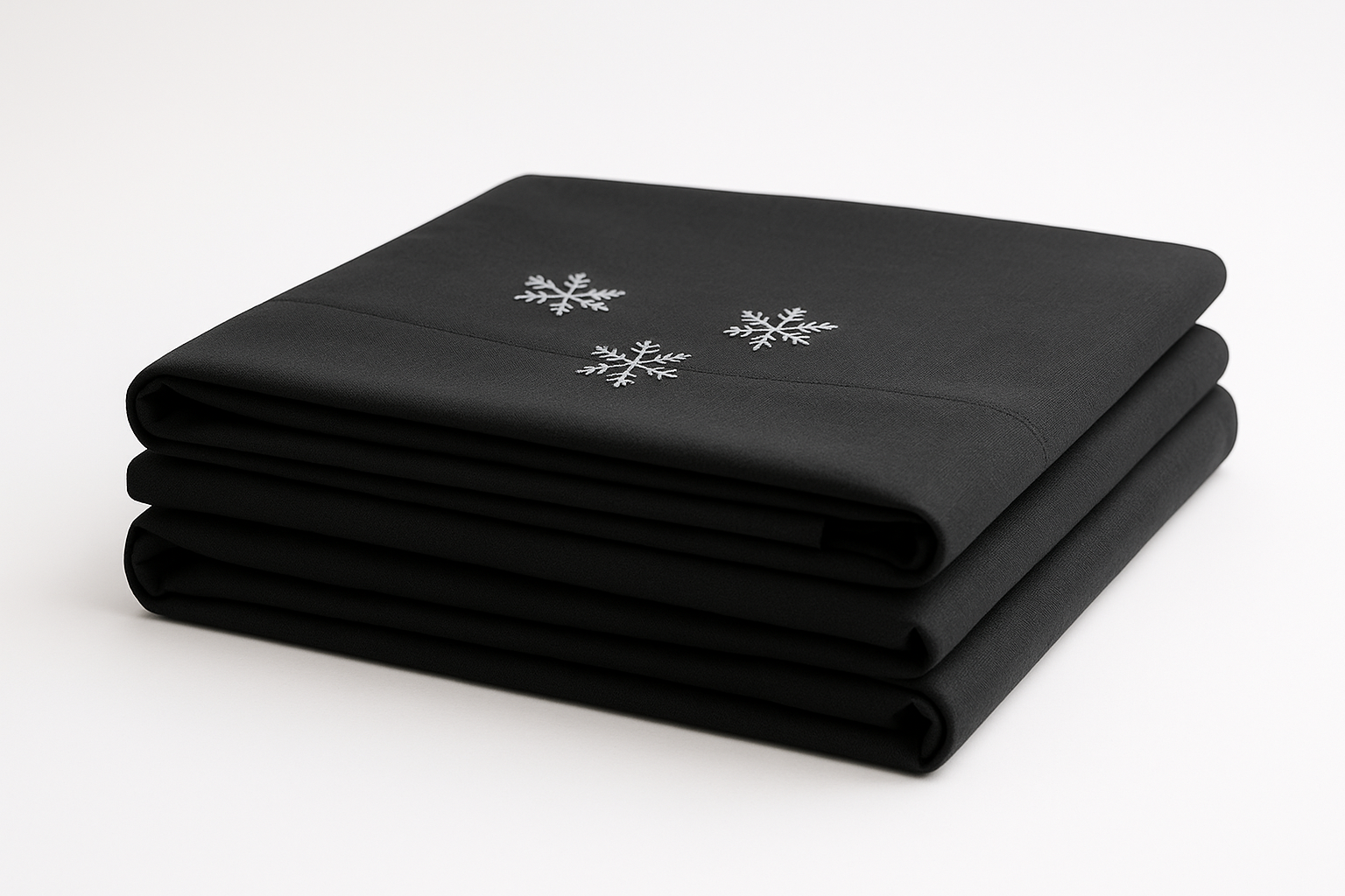 A neatly folded stack of black color cooling bed sheets with a small Snowflakes on top. 1:1 Minimalist product photography, clean white background, soft lighting, eco-friendly and natural aesthetic.